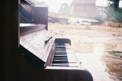 Rain splattered piano outside with rubble in background